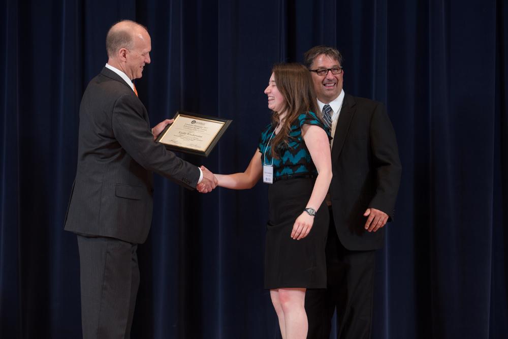 Doctor Potteiger shaking hands with an award recipient in a teal and black shirt